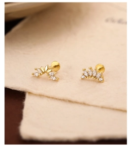 Macro shot of gold-plated silver ear studs with marquise-cut zircon in fan and floral shapes