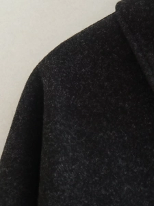 Détail en gros plan montrant la texture et la fibre du tissu en laine gris foncé