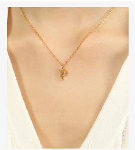Detail shot of a delicate gold P-letter pendant with sparkling small zircon on model