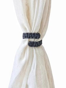 Detail of dark grey macrame cotton rope curtain tiebacks on white linen drapes
