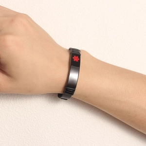 Detail of a medical alert bracelet with a black metal mesh band and red medical star logo