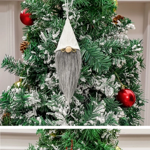 Detail of a Christmas gnome ornament with white knit hat and gray beard on a festive tree