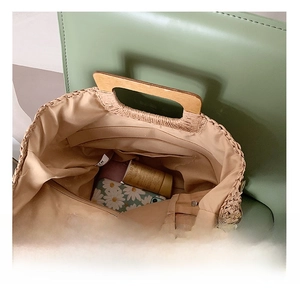 Straw handbag interior with wood handles showing daisy phone case and cosmetic storage