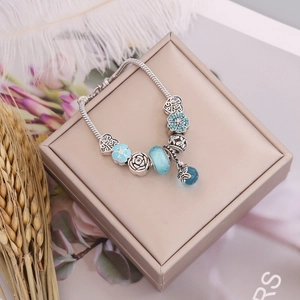 Detailed macro view of a beaded snake chain bracelet with blue glass beads and bird charms