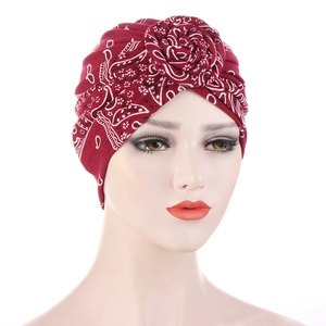 Detail of red paisley turban hat featuring a 3D rose knot on a professional mannequin