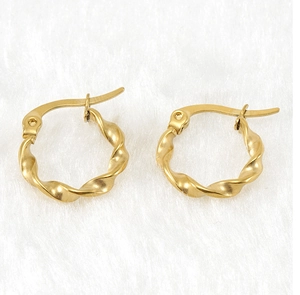 Macro detail of gold twisted hoop earrings with a textured spiral design on white fur