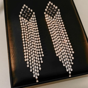 Macro shot of silver diamond rhombus tassel earrings with sparkling rhinestones on black leather