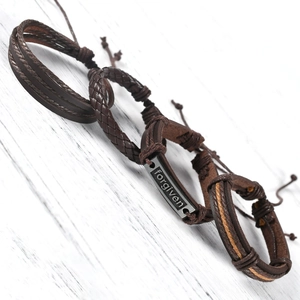 Macro shot of a braided brown leather bracelet with an engraved forgiven metal plate