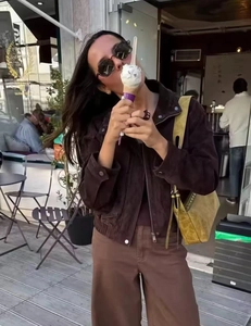 Scatto esterno di una giacca con zip da donna marrone e pantaloni larghi abbinati