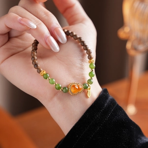 Close-up of retro orange garnet jade gourd bracelet with wood beads on wrist