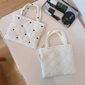 Dettaglio di borsa trapuntata bianca con ricamo e borsa per cellulare a pois neri imbottita