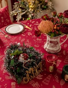 Close-up of red Christmas tablecloth with golden festive bells and tree patterns