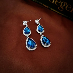 Detailed view of double drop blue crystal earrings on elegant brown silk background