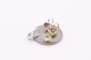 Macro shot of S925 sterling silver heart charms with red zircon on a coin for scale