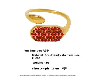 Détail d'une bague ouverte en acier doré sertie de pierres de zircon rouge