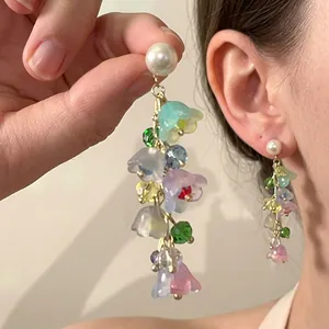 Detail of colorful floral tassel earrings with pearl studs and long petal fringe