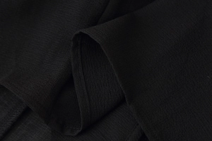 Detailed macro view of black ribbed knit fabric texture and high-quality edge stitching