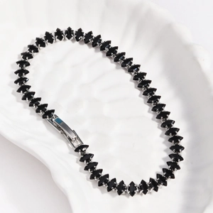 Macro detail of marquise-cut black zircons and silver fold-over clasp on tennis bracelet
