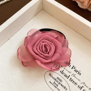 Detaillierte Nahaufnahme eines rosa Chiffon-Rosen-Haargummis mit weichen Stoffblättern