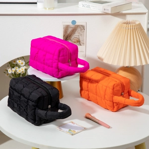 Quilted cosmetic bags in pink, orange, and black with durable handles and metal zippers