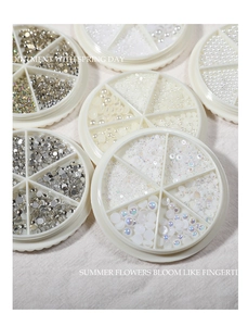 Flat back nail art rhinestones and pearls in round storage cases on beige linen fabric