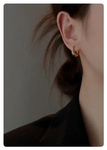 Primo piano dell'orecchino a cerchio huggie d'oro lucido indossato con stile minimal