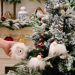 Detail showing lighted Christmas faceless gnome ornaments hanging on a festive tree branch
