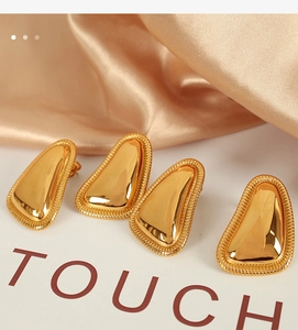 Detail of 18K gold-plated geometric paw earrings with braided edges on satin
