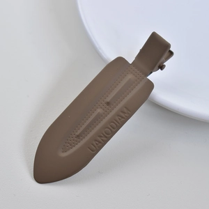 Detailed close-up of a matte brown acetate hair clip with UANODIAM engraving