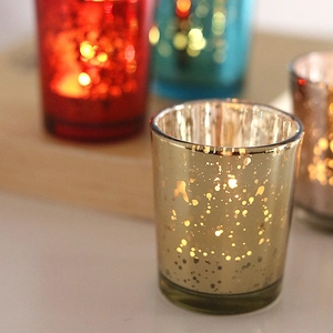 Starry electroplated silver glass candle holders in gold, red and blue on a wooden tray