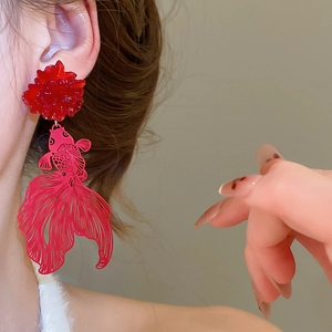 Detailed view of red resin flower and hollowed goldfish drop earrings worn by model