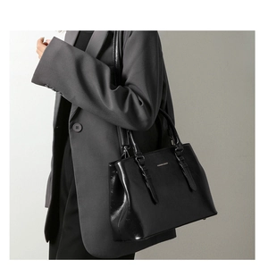 Detail of black faux leather handbag with golden Fashion & Bags logo and textures