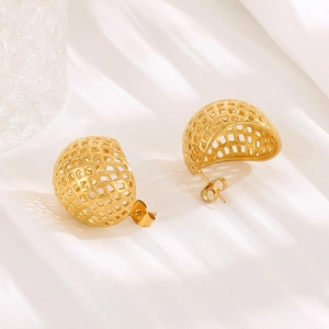 Macro detail of golden hollow mesh sphere earrings on elegant white satin fabric