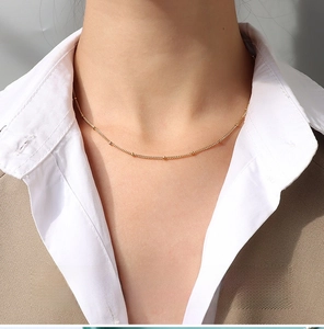 Detailed view of a 1.5mm gold-plated curb bead chain on a female model neck
