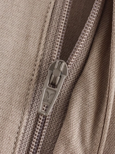 Macro shot of khaki textured fabric jacket with high-density stitching and matching zipper
