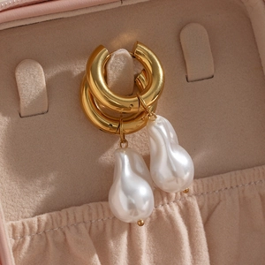 Detail view of Baroque pearl earrings on hooks inside a pink jewelry display box