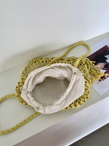 Detail view of woven shoulder bag featuring yellow mesh exterior and beige drawstring liner