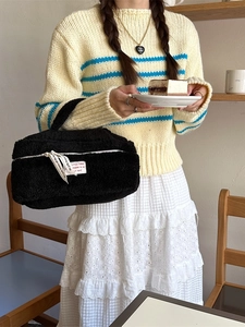 Portable black plush makeup bag with thick texture and stylish white ribbon handle