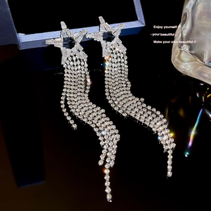 Macro view of glittering silver star earrings with long tassel chains and zircon inlays