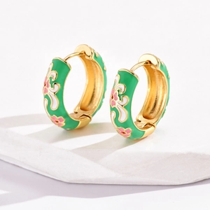 Macro detail of vintage floral enamel earrings with green base and pink flower pattern