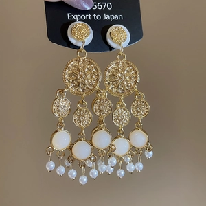 Vue détaillée de boucles d'oreilles dorées vintage avec pompons en perles blanches