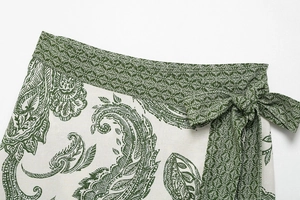 Detail of green and white paisley print mini skirt with a waist tie bow closure