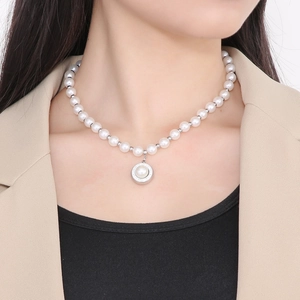 Detail of elegant French style pearl necklace with round pendant on model's neckline