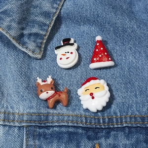 Nahaufnahme von vier Weihnachtsbroschen mit Schneemann, Weihnachtsmann und Rentier auf Denim