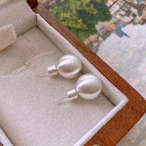 Macro detail of silver brushed round stud earrings on a wooden jewelry box velvet lining