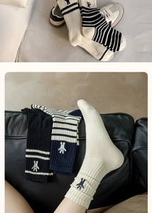 Detail of striped cotton socks with rabbit embroidery in cream, navy and black colors