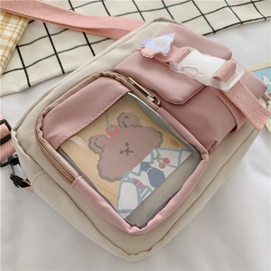 Detail view of pink canvas crossbody bag featuring clear front pocket and cute bear card