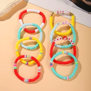 Detailed flat lay of colorful handmade Heishi clay bead bracelets with letter charms