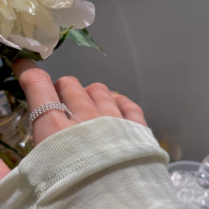 Detailed view of a silver bead chain ring worn with a floral background for a soft aesthetic