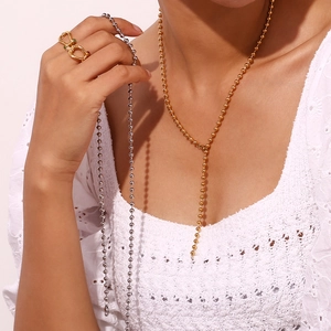 Detail of 4mm bead chain necklaces in gold and silver with a gemstone ring on model